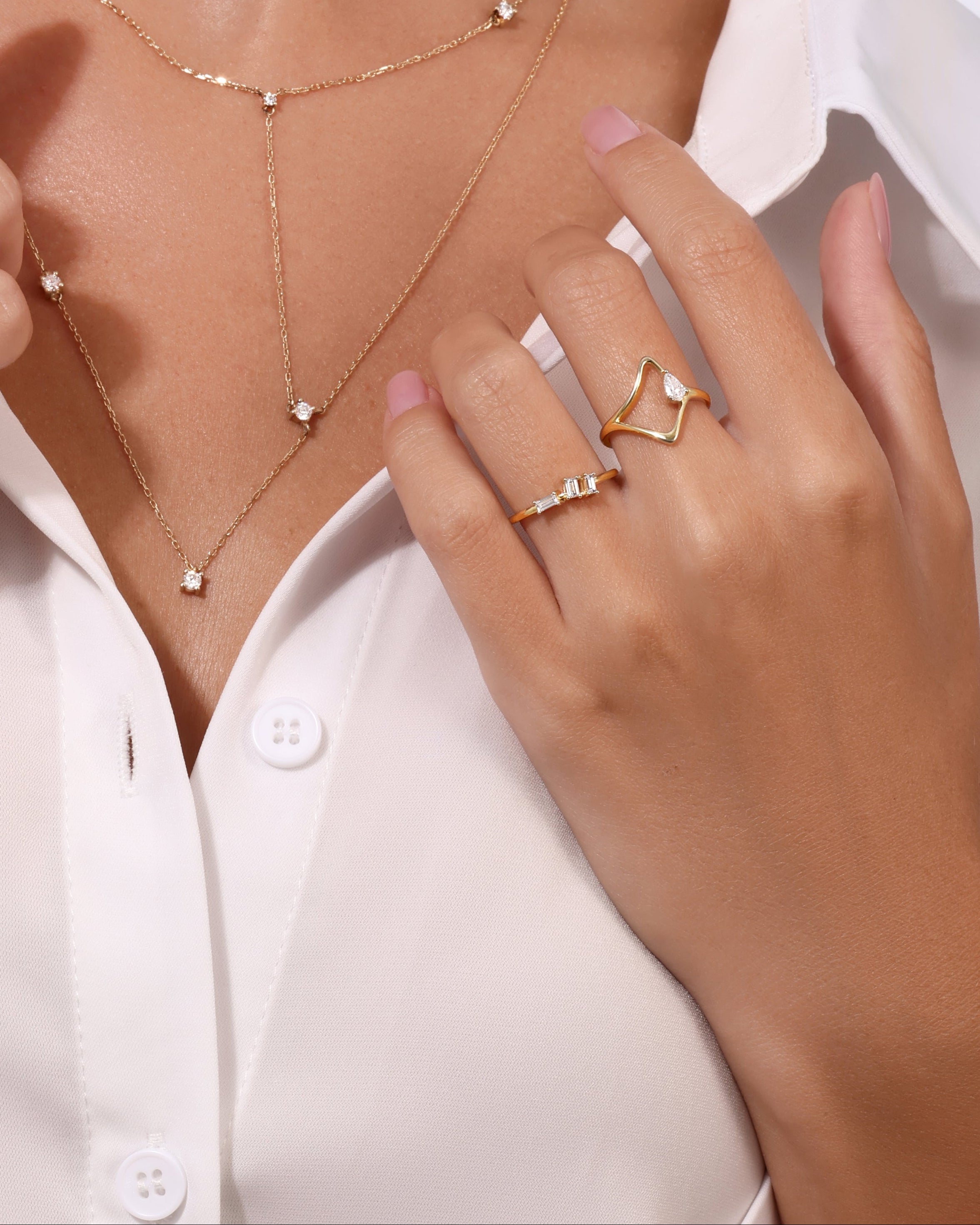 Woman wearing a gold necklace and rings on a white background