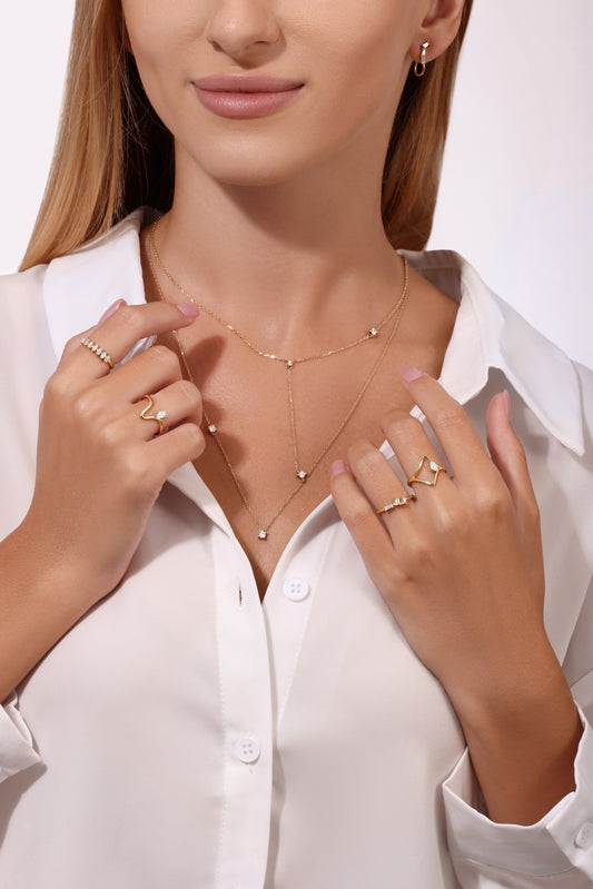 Woman wearing gold necklaces and rings on a white background