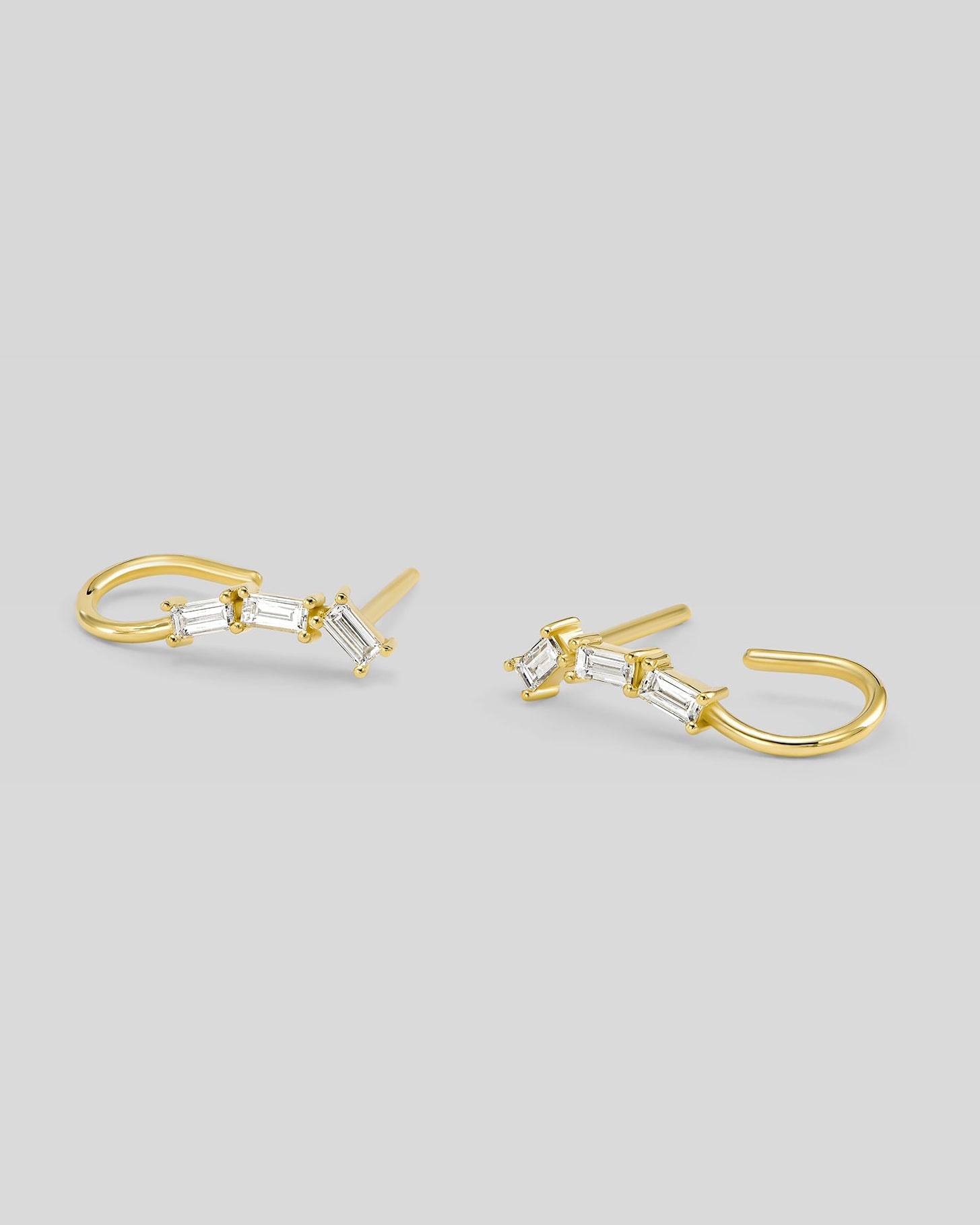 Gold hoop earrings with clear gemstones on a light gray background