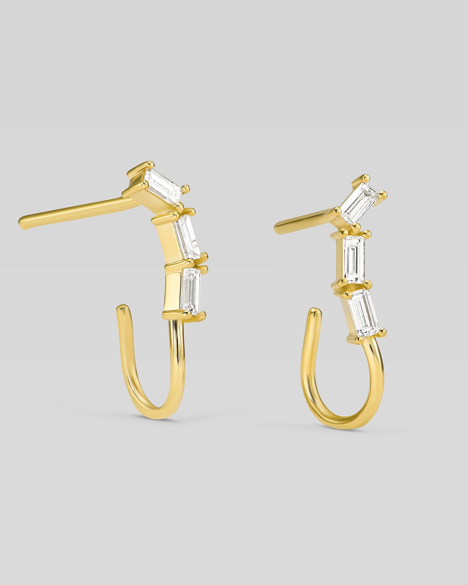Gold hoop earrings with clear gemstones on a gray background