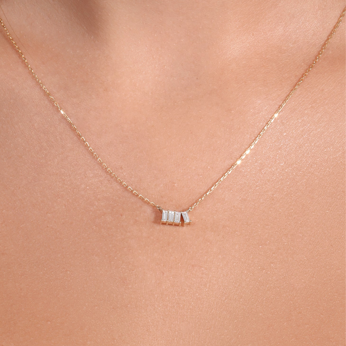 Gold necklace with a small pendant on a person's neck