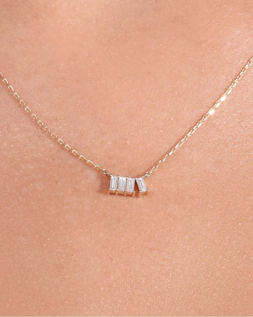 Gold necklace with a small pendant on a person's neck