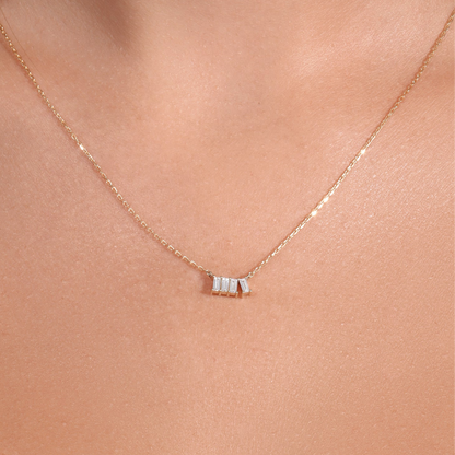 Gold necklace with a small pendant on a person's neck