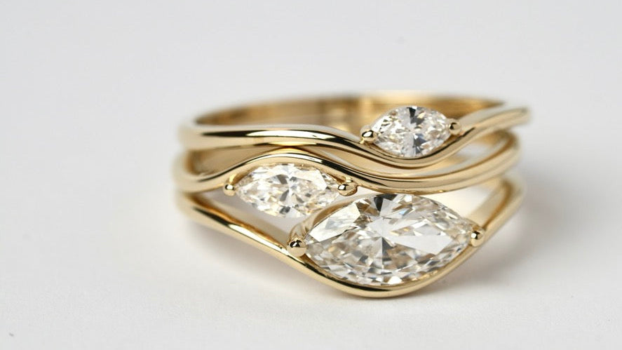 Gold ring with three diamond stones on a light gray background