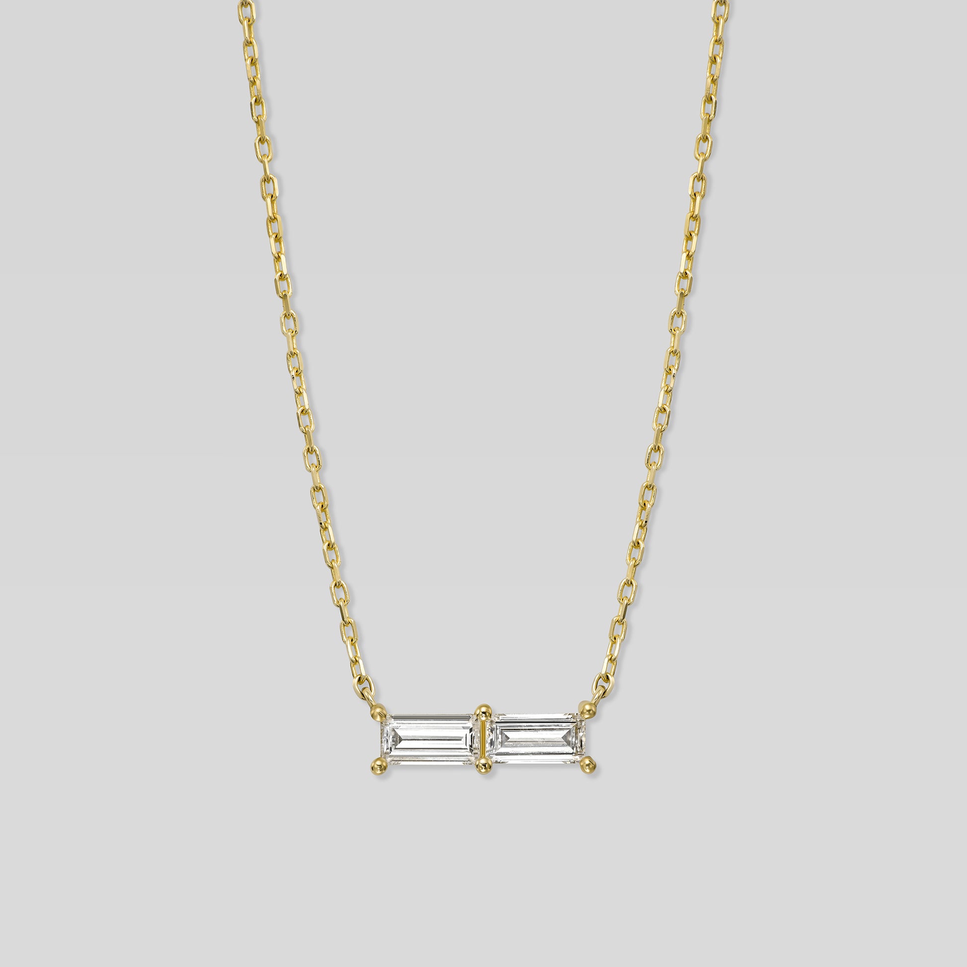 Gold necklace with a rectangular diamond pendant on a light gray background