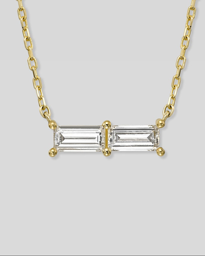 Gold necklace with a rectangular diamond pendant on a light gray background