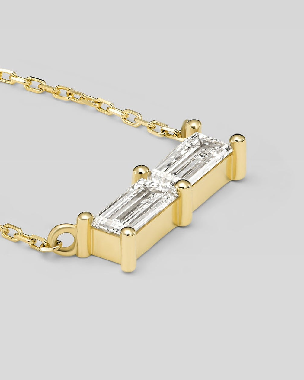 Gold necklace with a rectangular diamond pendant on a light gray background