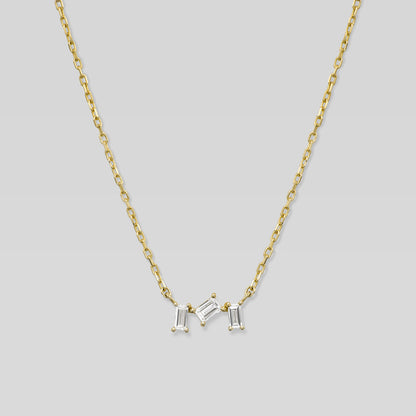 Gold necklace with three baguette-shaped diamonds on a light gray background