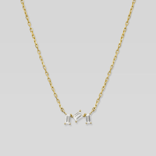 Gold necklace with three baguette-shaped diamonds on a light gray background