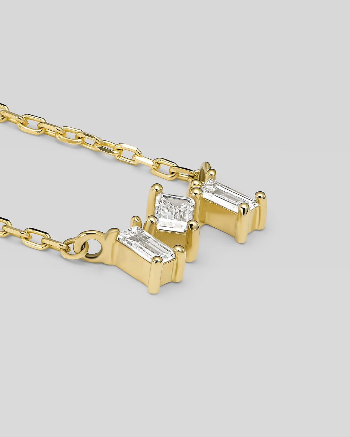 Gold necklace with diamond pendants on a light gray background