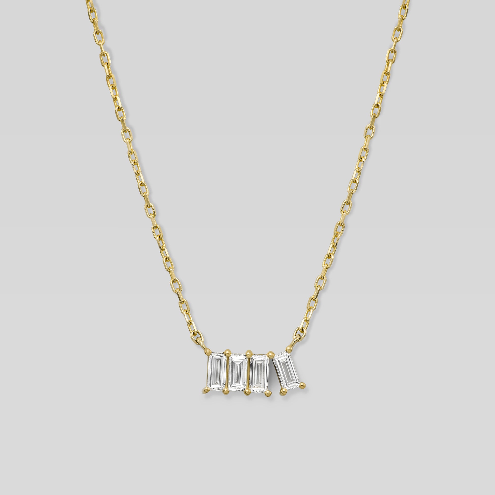 Gold necklace with four baguette-cut diamonds on a light gray background