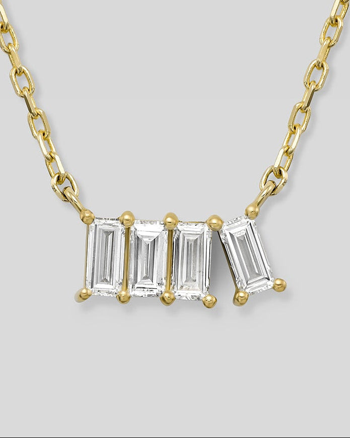 Gold necklace with four baguette-cut diamonds on a light gray background