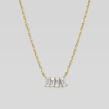 Gold necklace with four baguette-cut diamonds on a light gray background
