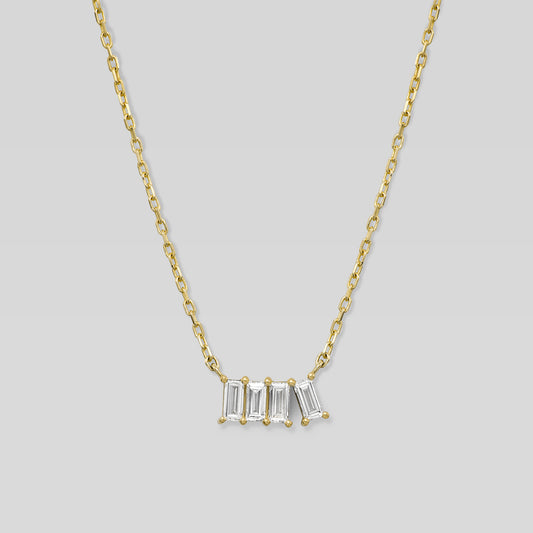 Gold necklace with four baguette-cut diamonds on a light gray background