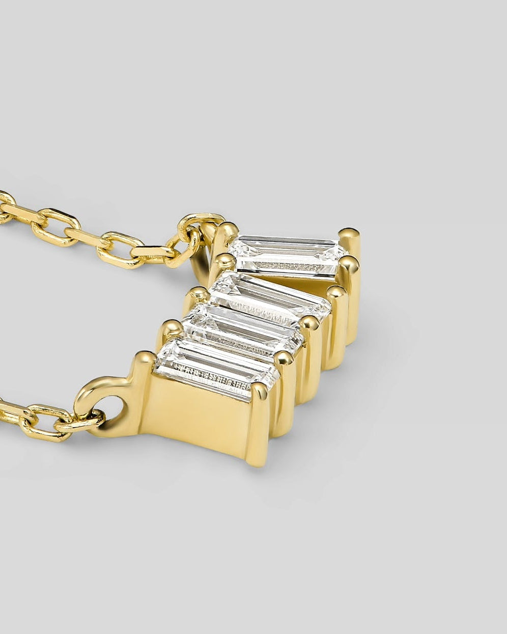 Gold necklace with four baguette-cut diamonds on a light gray background