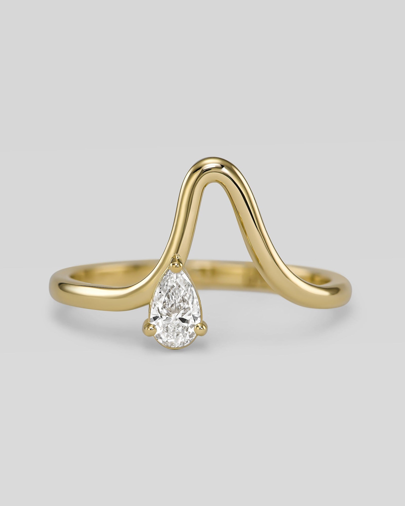 Gold ring with a teardrop-shaped diamond on a light gray background
