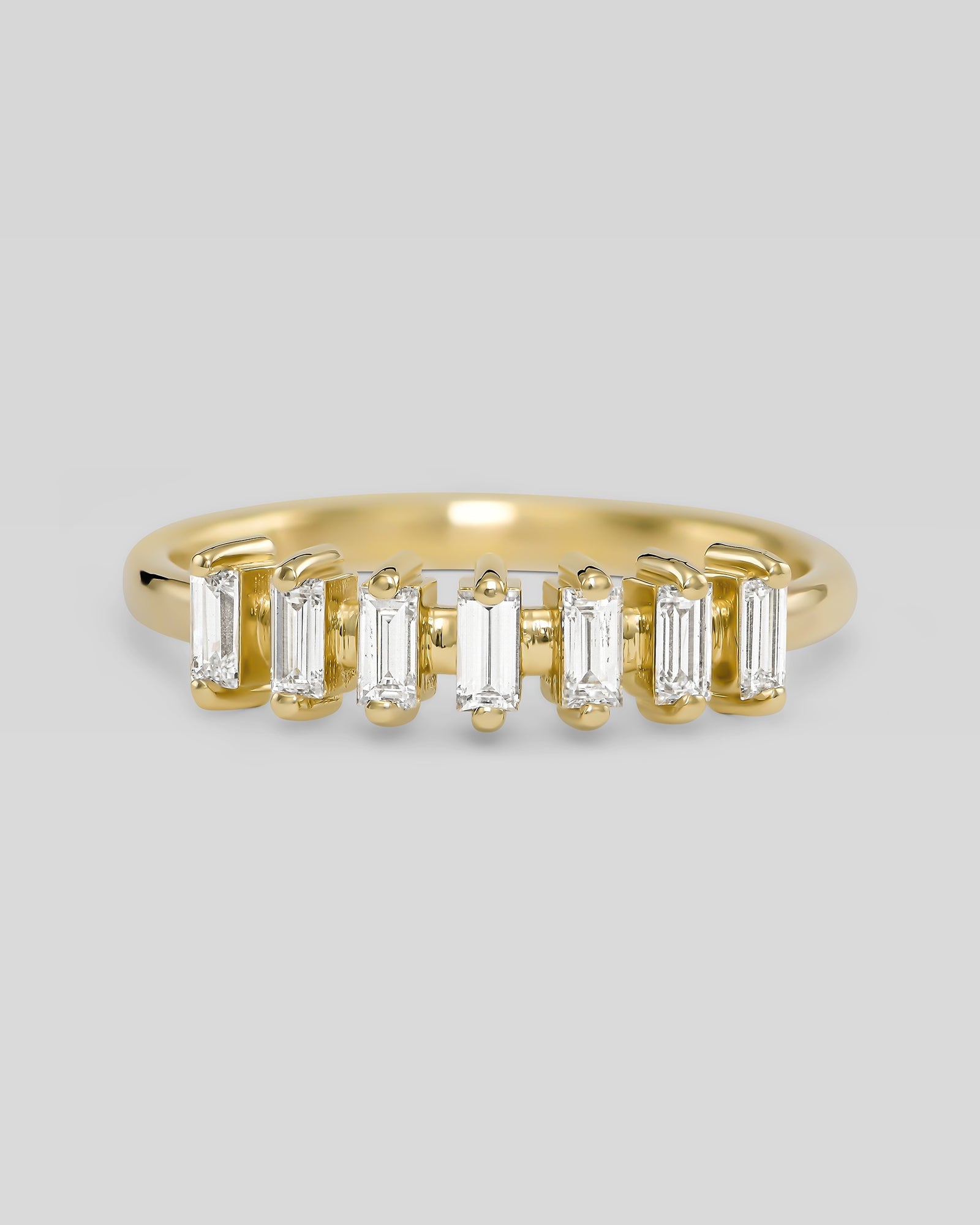 Gold ring with baguette-cut diamonds on a light gray background