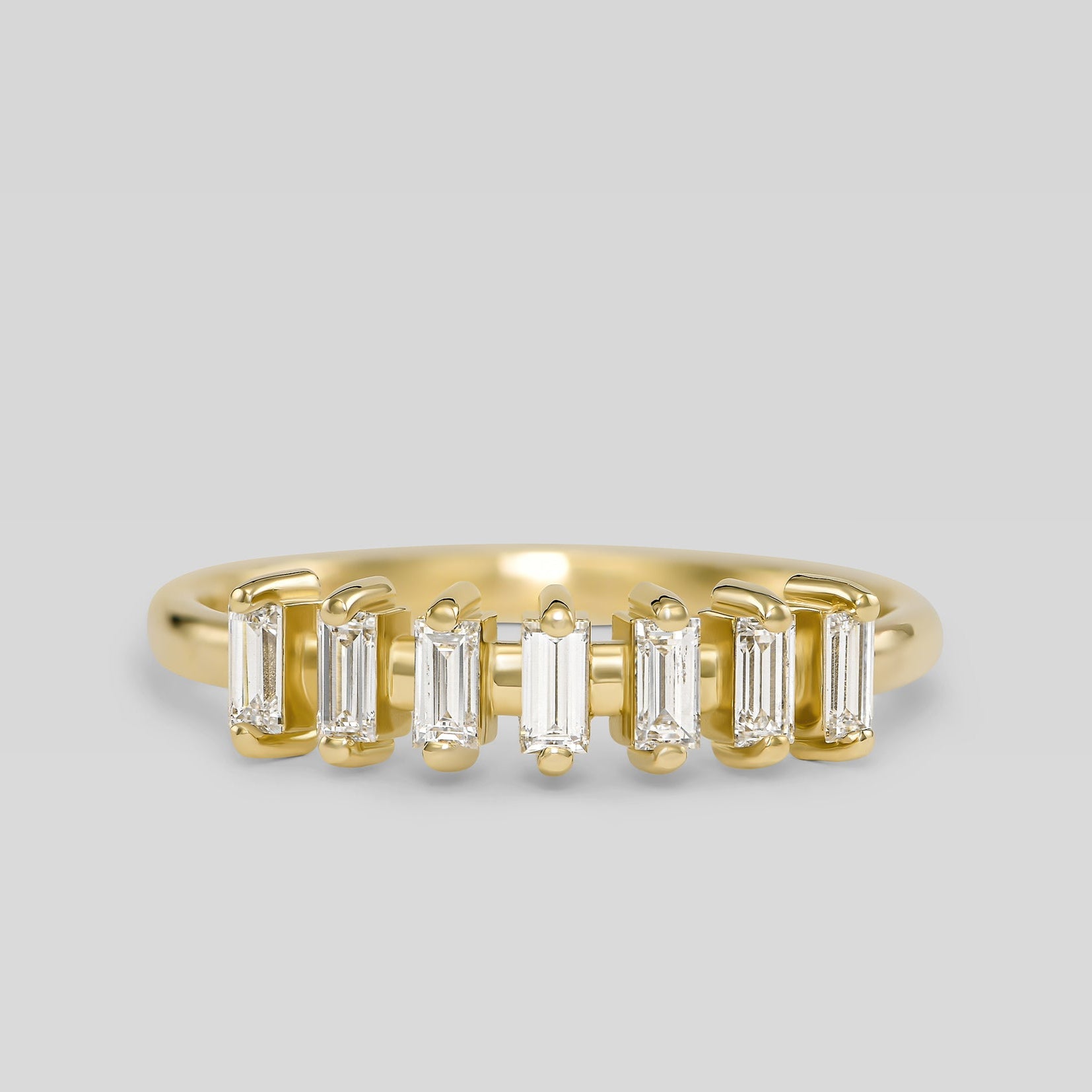 Gold ring with baguette-cut diamonds on a light gray background