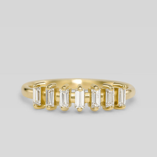 Gold ring with baguette-cut diamonds on a light gray background