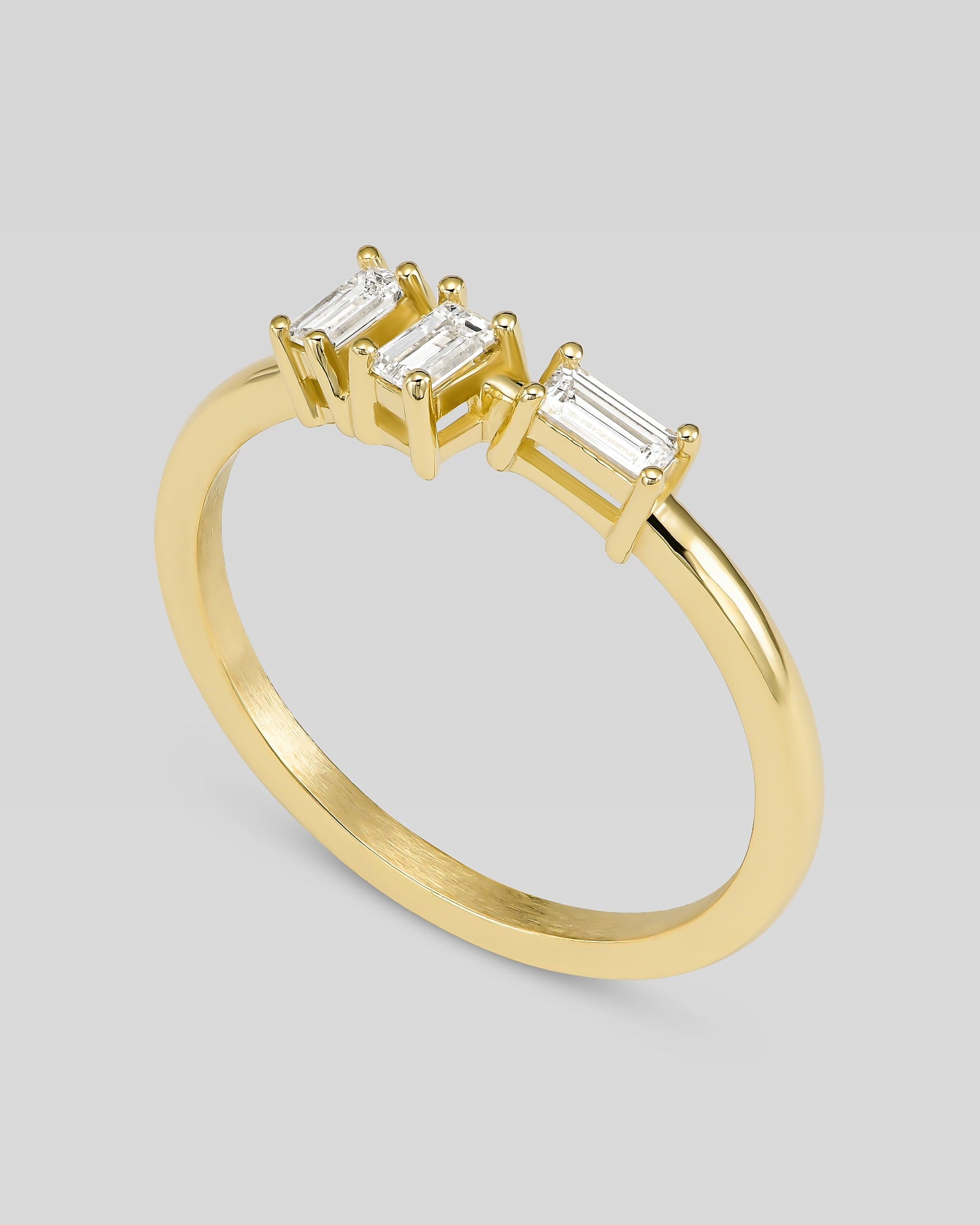 Gold ring with three baguette-cut diamonds on a light gray background
